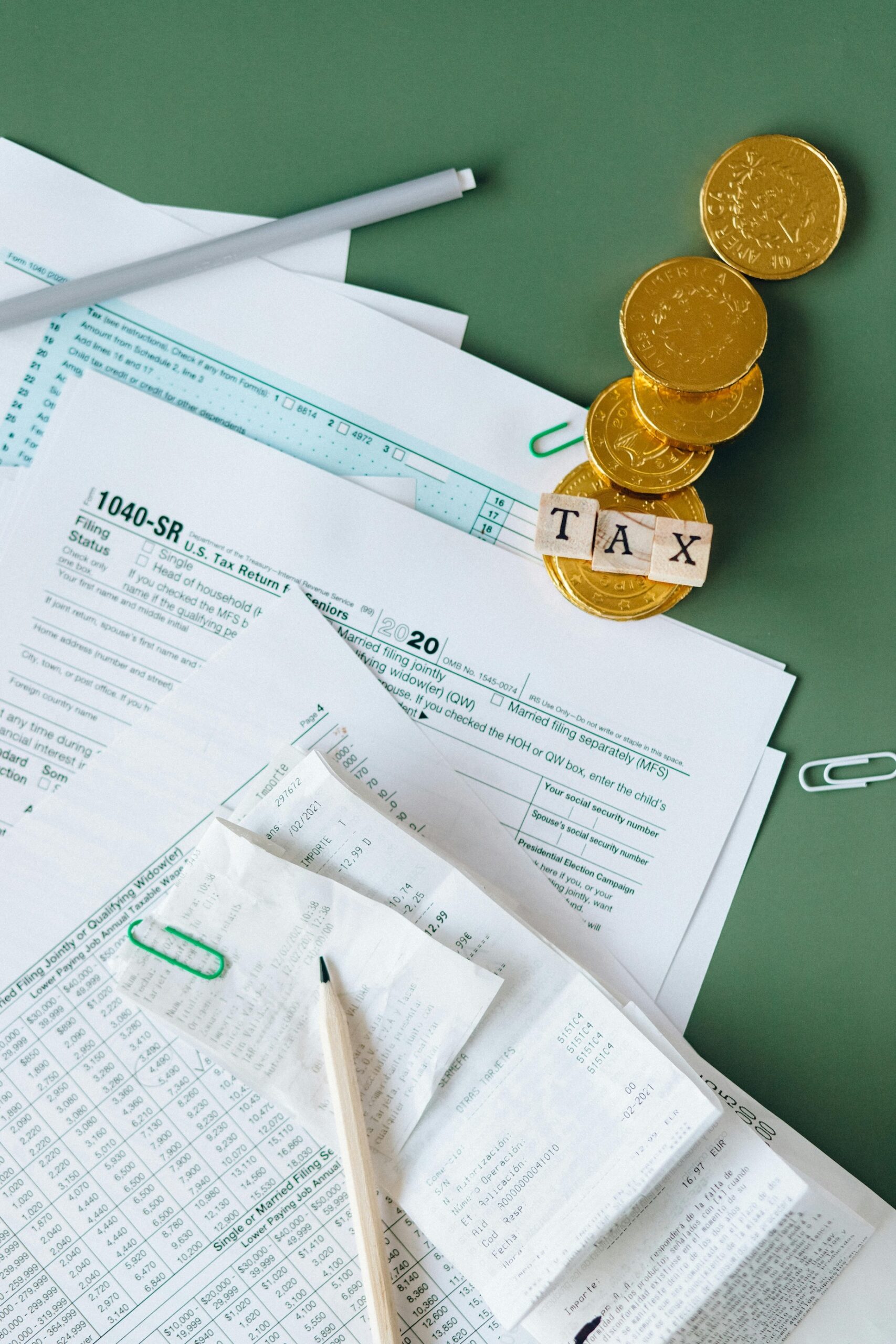 Stock photo of tax forms, pencils, coins, and a paper clip